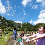 青空の下ではじけるシャボン玉と水しぶき。子どもらが水をかけ合った＝神河町猪篠（撮影・辰巳直之）