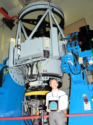 「なゆた望遠鏡」（奥）の未来技術遺産登録を喜ぶ伊藤洋一・県立大学西はりま天文台センター長＝佐用町西河内