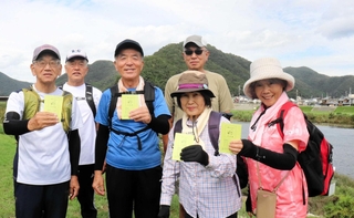 千種川をバックに集う「うさぎとかめ」のメンバーら。元気帳を持ち、運動を楽しむ＝上郡町内