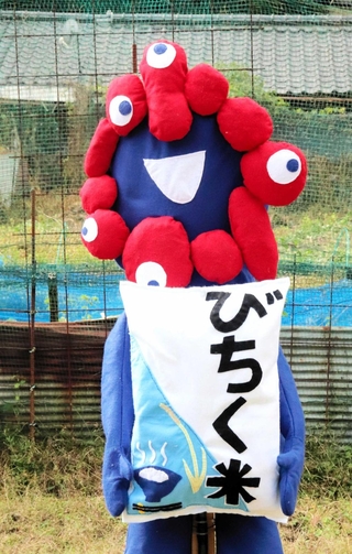 「備蓄米」の袋を持つミャクミャク＝相生市矢野町瓜生