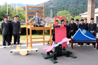 高校生が作った巨大椅子の座り心地を確かめる山名宗悟町長（中央）＝神河町寺前