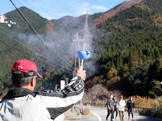 ウオーキングイベントのコース上でロケット花火を打ち上げる関係者＝神河町栗