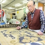 赤穂緞通の染み抜きで、表面の状態を確認する田川芳弘さん＝赤穂市坂越