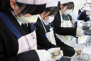 カキの殻むきを体験する生徒ら＝双葉中学校