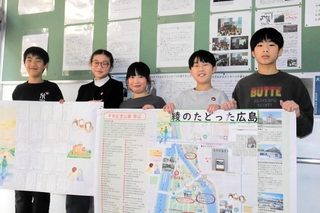 平和学習の成果をまとめたポスターを持つ児童ら＝山野里小学校