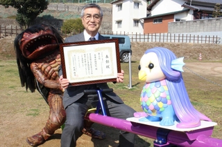 辻川山公園に新設されたシーソーに座って表彰を喜ぶ尾﨑吉晴町長とガジロウ＝福崎町西田原