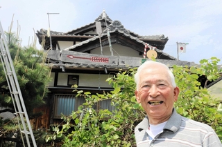 自作のペーロン模型を屋根に取り付けた川崎久令さん＝相生市那波大浜町