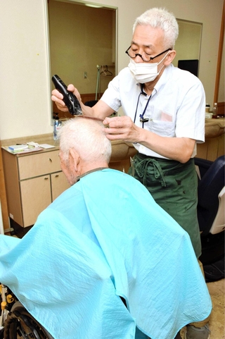 車いすに乗った入院患者を散髪する理容師＝たつの市新宮町光都