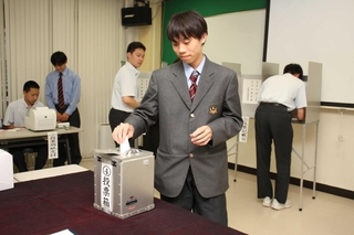 選挙で実際に使われている記載台や投票箱などを使って一票を投じる生徒たち＝神河町福本、神崎高校