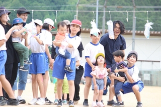 駆けっこに参加した未就学児を抱っこして、手作りのプレゼントを選んでもらう児童ら＝市川町上瀬加