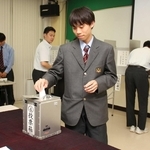選挙で実際に使われている記載台や投票箱などを使って一票を投じる生徒たち＝神河町福本、神崎高校