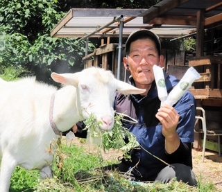 ヤギミルクのアイスバーを持つ岡部強志さんと、原料の乳を出す「ナナ」＝上郡町金出地