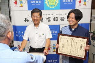 感謝状を受けた但陽信用金庫寺前支店の後藤考司支店長（左）とローソン福崎南田原店の松本雄樹店長＝福崎町福崎新、福崎署