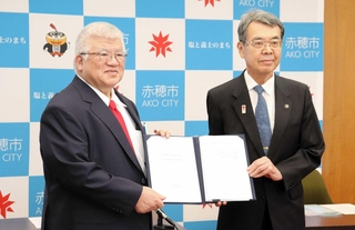 「公立赤穂中央市民病院」などの管理に関する基本協定書を手にする赤穂市の牟礼正稔市長（右）と医療法人「伯鳳会」の古城資久理事長＝赤穂市役所