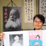 大鳥みちのアニメ画と、胸像の写真のコピーを持つ中川由香さん。背後には、大鳥圭介の肖像が掲げられている＝上郡町岩木丙、いきいき交流ふるさと館