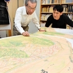 池田善考さん（左）が製作した重ね図。たつの市役所などがある地域（絵図の手前）が、江戸期は揖保川だったことが分かる＝たつの市龍野町上霞城