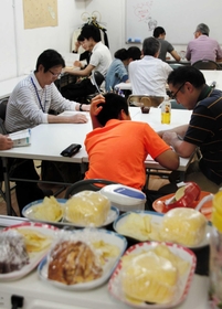 ボランティアから勉強を教わる中学生。寄付による軽食も用意されている＝神戸市内