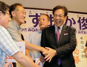 豊岡高時代の同級生らの祝福を受ける水岡俊一氏（右）＝２１日午後８時３６分、東京都千代田区