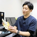 「この病気を治療して活動量が増えると、健康寿命を伸ばすことにもつながる」と、背骨の模型を手にしながら話す宮﨑真吾医師＝神戸市中央区旭通４、あんしんクリニック