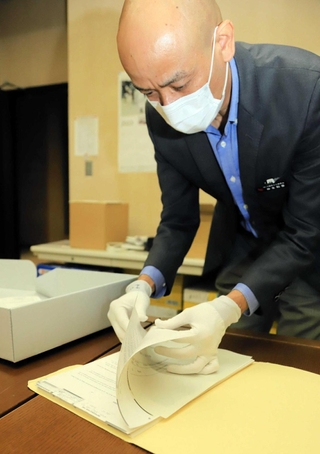 米国立公文書館で収集した資料を見せる仲本和彦さん。大量の資料の中には、沖縄返還交渉時の密約文書もあったという＝沖縄県南風原町、同県公文書館