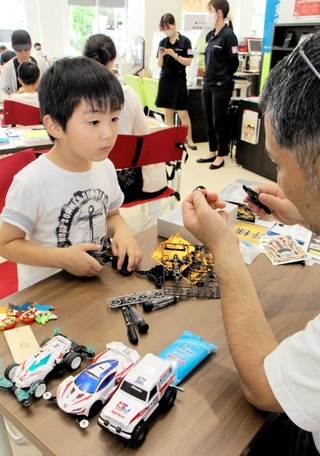 トヨタ車の販売店内でミニ四駆作りをする親子＝三田市すずかけ台３、ネッツテラス新三田