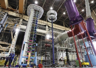 上部に小さな円盤が連なる左側の太い柱がインパルス電圧発生装置本体。右隣の大きな二つの輪が重なる柱は専用測定器。変圧器（右下）に高圧の電流を流して試験を行う＝いずれも赤穂市鷆和（撮影・三浦拓也）