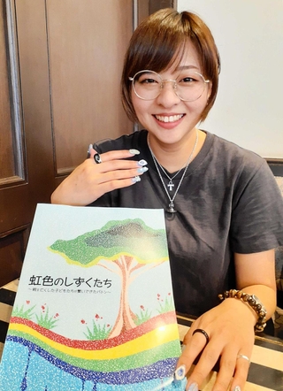 ファシリテーター向け冊子「虹色のしずくたち」を持つ森田望奈未さん。表紙のデザインを手がけた＝神戸市中央区