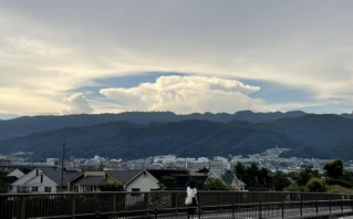 六甲山系の山々と住宅街の上空に広がった巨大な雲＝２６日午後、芦屋市内（撮影・三浦拓也）