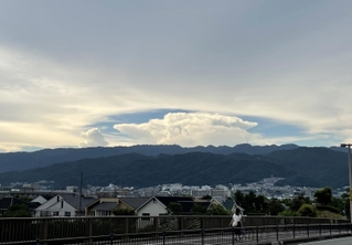 六甲山系の山々と住宅街の上空に広がった巨大な雲＝２６日午後、芦屋市内（撮影・三浦拓也）