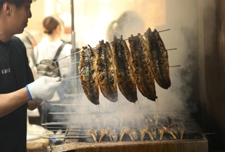 たれを絡めて香ばしく焼き上げられるウナギ＝２９日午後、明石市本町１