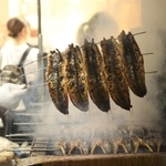 たれを絡めて香ばしく焼き上げられるウナギ＝２９日午後、明石市本町１