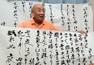 原爆の恐ろしさを短歌で伝え続ける小泉雄次さん。後ろに掲げた峠三吉の代表作について「一番被爆者の思いが込められている」＝伊丹市（撮影・中西幸大）