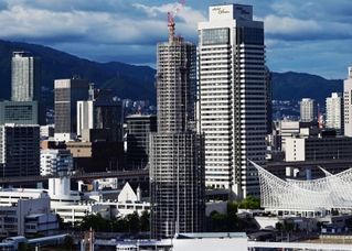 工事用のシートが外され、鉄骨の足場が西日を受けて輝く神戸ポートタワー＝７日午後、神戸市中央区東川崎町１から波止場町方面を望む