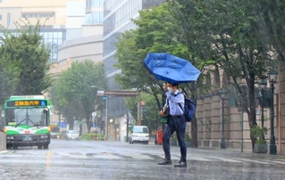 お盆と台風の影響で人けの少ない神戸・元町を、傘を差して歩く人＝１５日午前９時３２分、神戸市中央区（撮影・鈴木雅之）