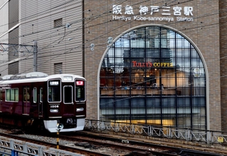 「タリーズコーヒーセレクト阪急三宮店」が入る神戸三宮阪急ビルのアーチ窓。マルーンカラーの阪急電車が目の前を走る＝神戸市中央区加納町４