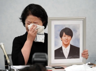 高島晨伍さんの写真を手に涙を拭う母淳子さん＝１８日午後、大阪市北区