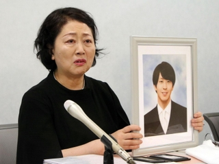 高島晨伍さんの写真を手に再発防止を訴える母淳子さん＝１８日午後、大阪市北区
