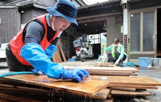泥をかぶった床板を洗うボランティア＝１８日、美町香住区間室