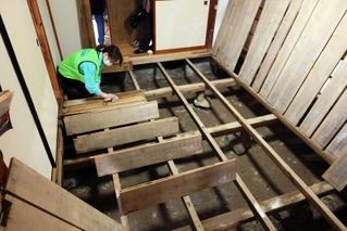 泥をかぶった床板を清掃するボランティア＝１８日、香美町香住区間室