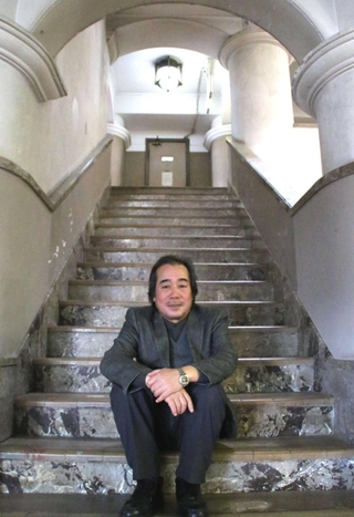 御影公会堂の階段に座る山本二三さん＝２０１６年３月、神戸市東灘区