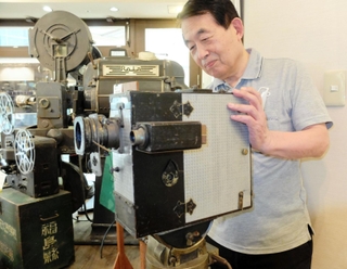 関東大震災の撮影に使われたとみられるカメラを手にする安井喜雄館長＝神戸映画資料館