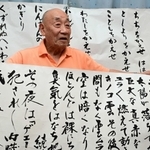 原爆の恐ろしさを短歌で伝え続ける小泉雄次さん。後ろに掲げた峠三吉の代表作について「一番被爆者の思いが込められている」＝伊丹市（撮影・中西幸大）
