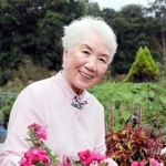 「偶然テレビで見たおかげで病気を発見できた。運が良かった」と育てた花々を手に笑顔を見せる藤本さよ子さん＝小野市内