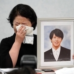 高島晨伍さんの写真を手に涙を拭う母淳子さん＝１８日午後、大阪市北区