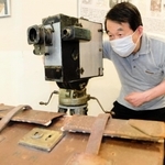 関東大震災の撮影に使われたとみられるカメラを手にする安井喜雄館長＝神戸映画資料館