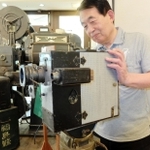 関東大震災の撮影に使われたとみられるカメラを手にする安井喜雄館長＝神戸映画資料館