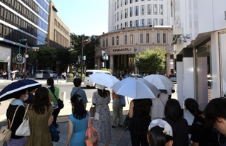 あまりの暑さに、日差しを避けて信号待ちをする人たち＝８月１２日、神戸市中央区三宮町３