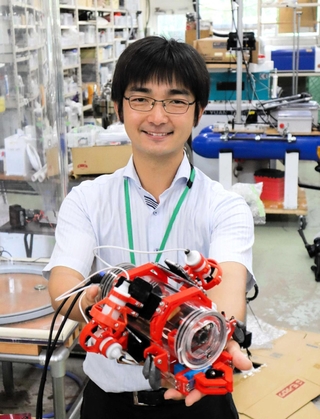 自作の水中ロボを手にする小沢正宜准教授＝神戸市西区学園東町８、市立工業高等専門学校