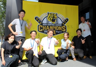 サンテレビ本社に掲げた阪神タイガースの主力選手のサイン入りフラッグを前に喜ぶスポーツ部のメンバー＝神戸市中央区東川崎町１