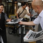 阪神優勝を伝える号外を笑顔で受け取る人たち＝１５日午前、ＪＲ神戸駅（撮影・三津山朋彦）